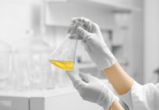 Hände halten Reagenzglas mit gelber Flüssigkeit in einem Labor