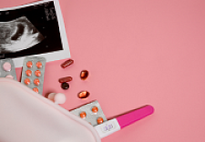 Tabletten. Schwangerschaftstest, Ultraschallbild liegen in der linken unteren Bildecke auf rosa Hintergrund
