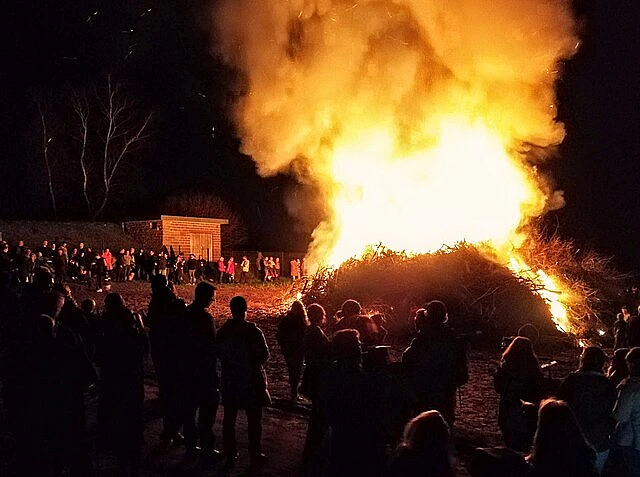 Menschen stehen am Osterfeuer