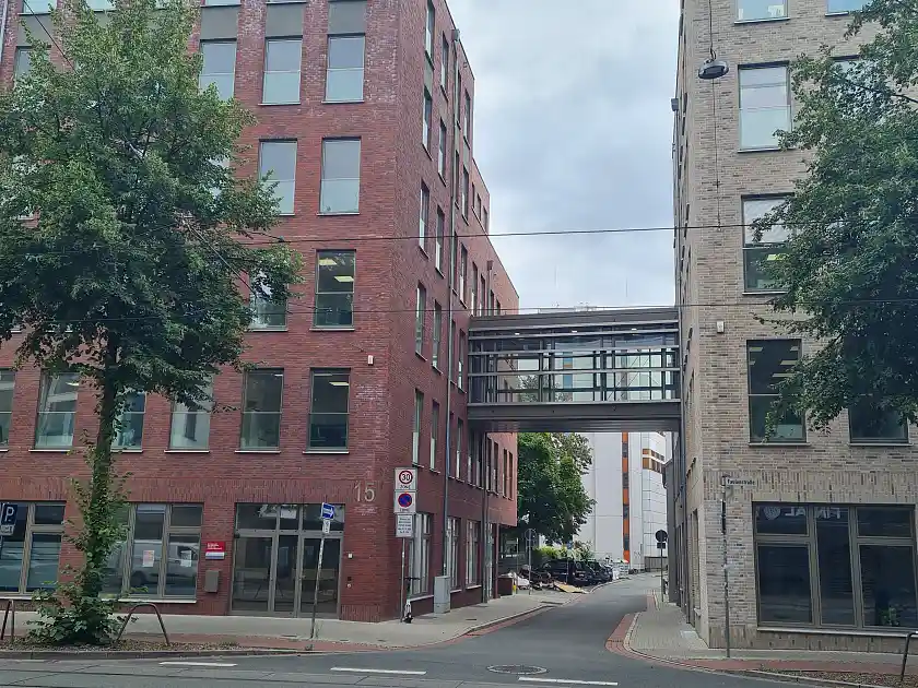 Das Dienstgeb&auml;ude von au&szlig;en vor der Nachr&uuml;stung. Man sieht eine Glasbr&uuml;cke, die zwei Geb&auml;ude verbindet.