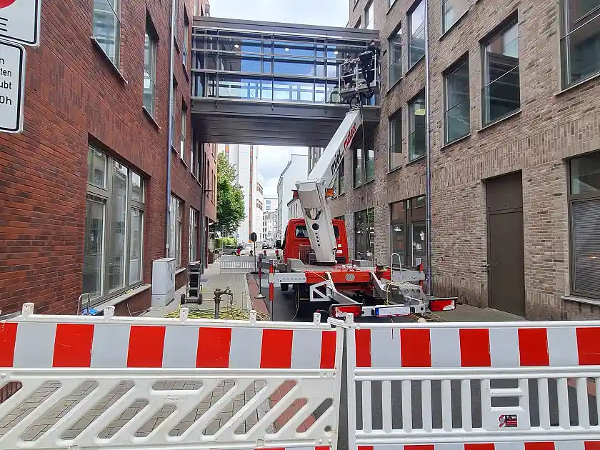 Die Straße ist abgesperrt und zwei Arbeiter reinigen vom Steiger aus die Fenster