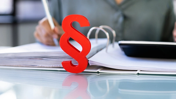 Rotes Paragrafenzeichen vor einem Aktenordner