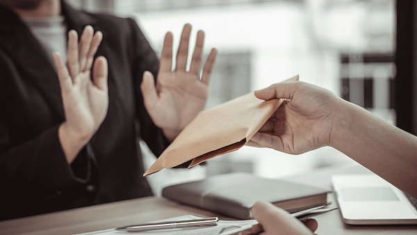 Umschlag mit Geld wird überreicht und mit Geste abgelehnt.