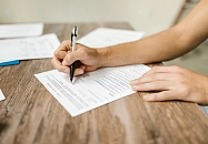 Eine Person unterschreibt ein Dokument.