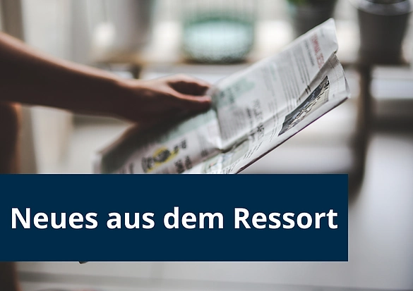 Man sieht eine Hand, die eine Zeitung hält.