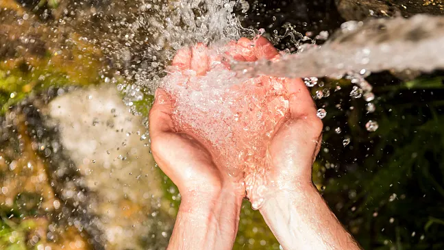 Es sind zwei Hände mit Wasser  zu sehen.