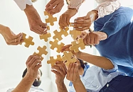 Viele Hände halten Puzzleteile. 